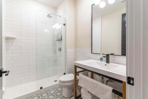 A modern bathroom with a glass-enclosed shower, a white sink, and a large mirror. - 2 Bedroom Suite (Frankfort)