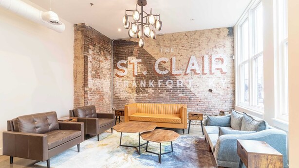 A modern interior with a brick wall, leather sofas, and a chandelier. - 2 Bedroom Suite (Frankfort)