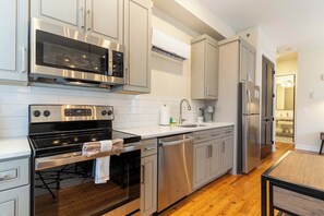 A modern kitchen with stainless steel appliances, white cabinetry, and a wooden floor. - Junior Suite, King (Frankfort)