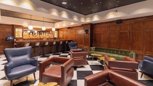 Una zona de bar con paneles de madera, sillas de cuero y suelo a cuadros.