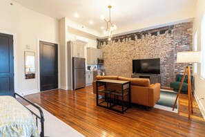 A modern living room with a sofa, a coffee table, a TV, and a brick wall.
