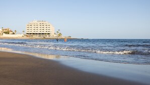 A beachfront hotel with multiple floors and balconies, located near the water.