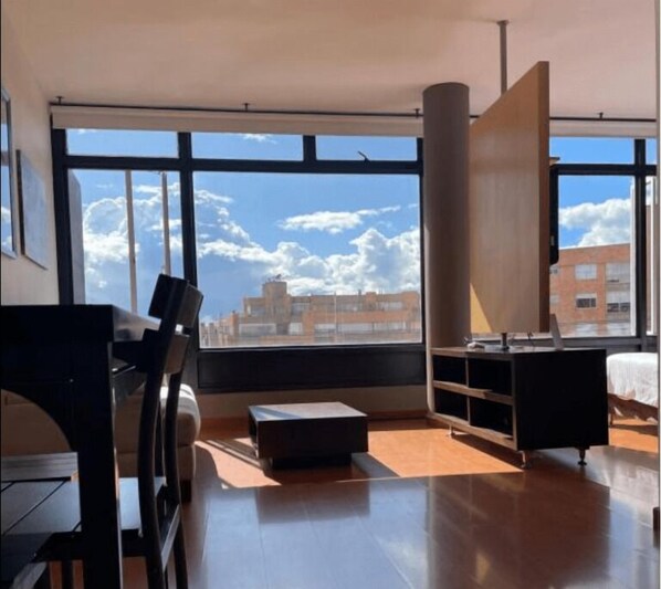 Enjoy a city view from the large window in this stylish room with a sofa, table, and cabinet.
