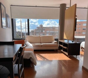 Enjoy a city view from the large window in this stylish room, featuring a sofa, table, and cabinet.