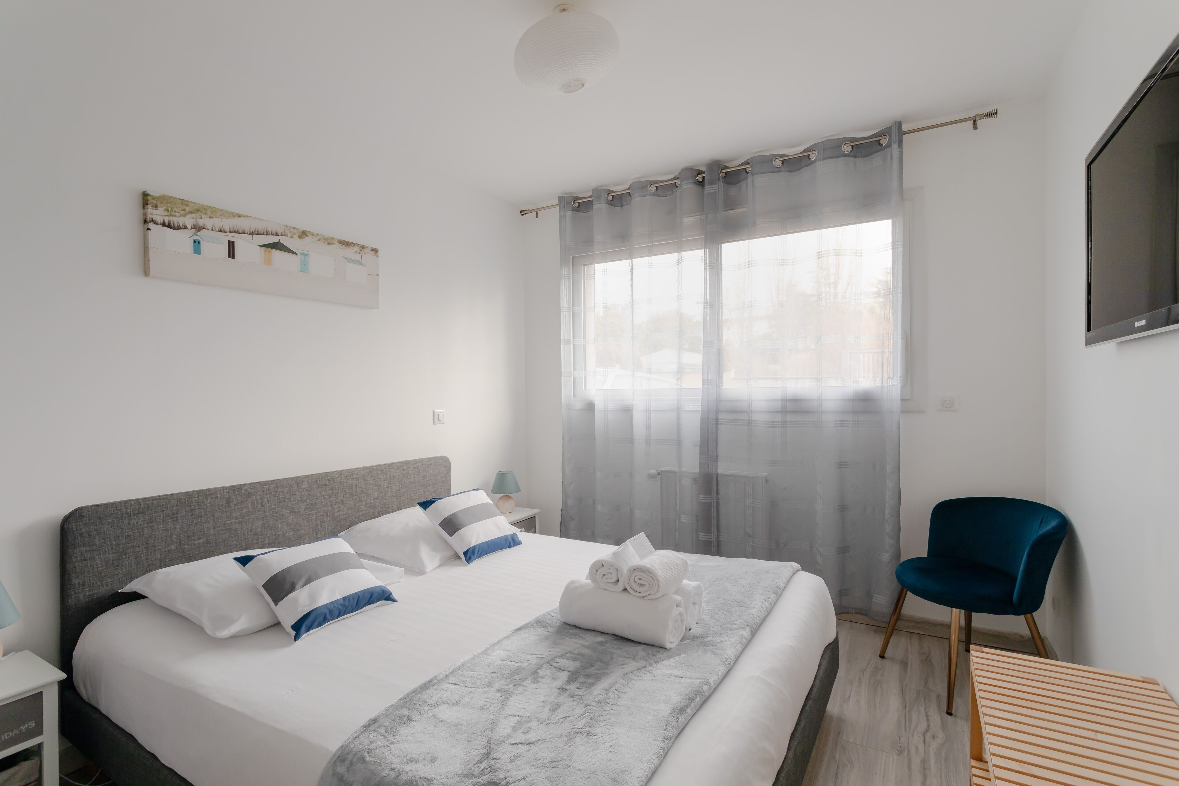 A modern hotel room with a large bed, a desk, a chair, and a TV.