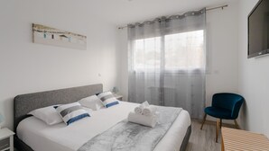 A modern hotel room with a large bed, a desk, a chair, and a TV. - Rosamaris - Maison pour 8 avec jardin (Saint-Malo)