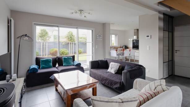 A modern living room with a sofa, a coffee table, and a dining area. - Rosamaris - Maison pour 8 avec jardin (Saint-Malo)
