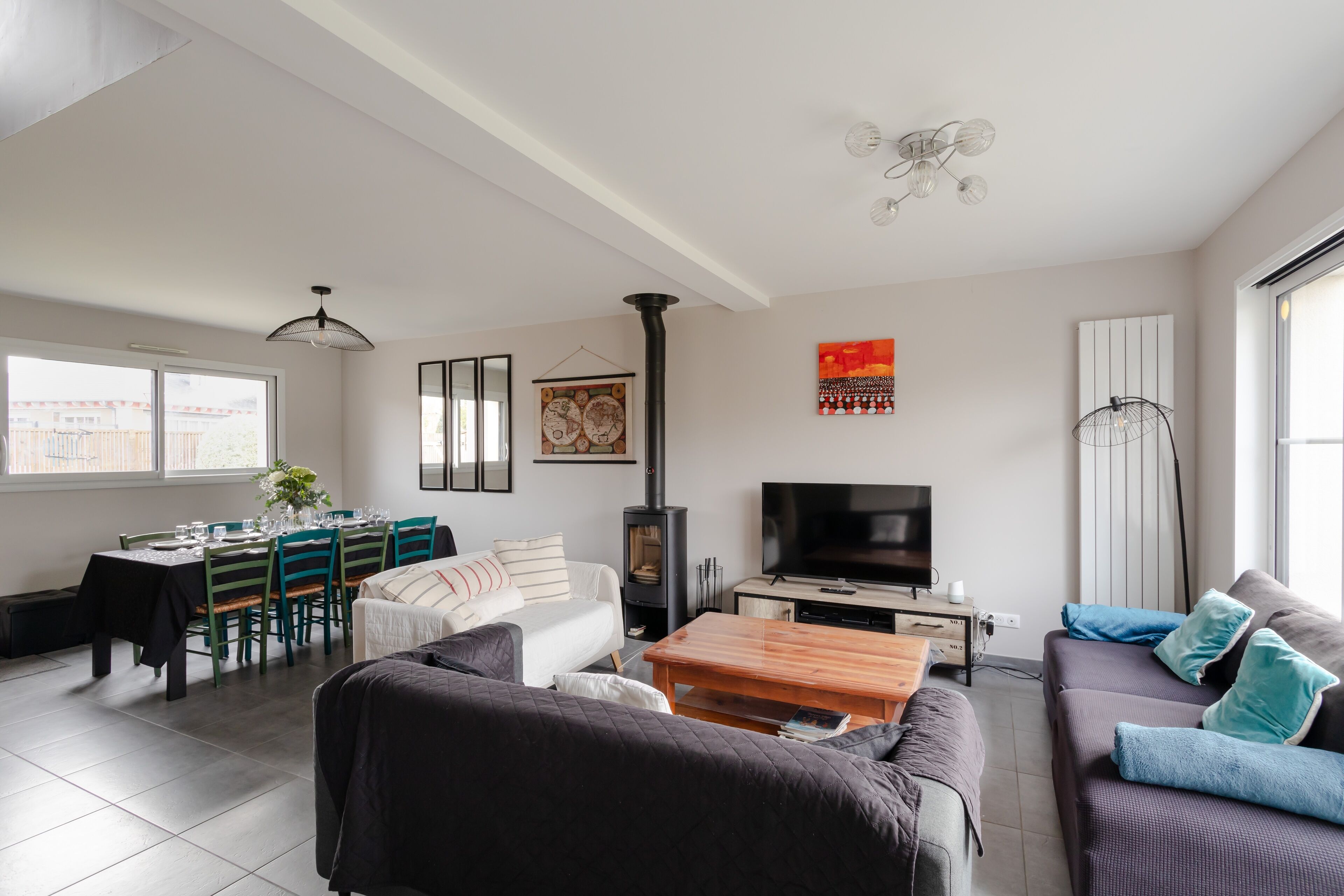 A modern living room with a sofa, a coffee table, a TV, and a dining area with chairs and a table.