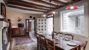 Un'area pranzo con un tavolo di legno apparecchiato per sei persone, circondato da sedie, un pavimento a scacchi e una lampada a sospensione rossa.