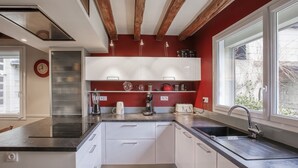 Una cucina moderna con mobili bianchi, un piano di lavoro nero e una finestra che lascia entrare luce naturale.