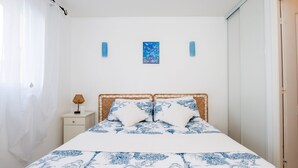 Une chambre à coucher avec un lit, une table de chevet, un tableau accroché au mur et une porte.