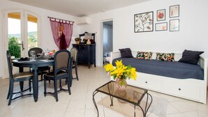 Une pièce comprenant une table à manger, des chaises, un canapé et une table basse en verre sur laquelle est posé un vase de fleurs.