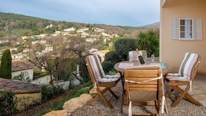 Une terrasse avec une table et des chaises donnant sur un village perché sur une colline.