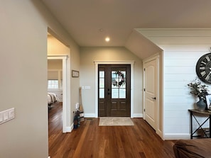 A hallway with wooden flooring, a dark brown door, and a wall clock. - 7th Heaven by Taylor Made Deep Creek (McHenry)