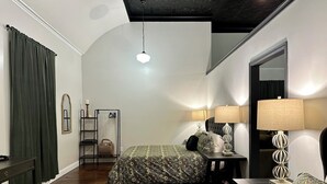 A bedroom with two beds, a nightstand, a dresser, a mirror, and a hanging light fixture.