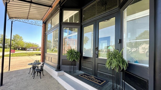 A building with large windows, a covered porch, and a welcome mat.