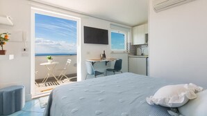 A bedroom with a bed, a desk, and a chair. There is a balcony with a view of the sea. - BEAUTY HOME SORRENTO (Sorrento)