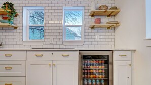 A kitchen with white cabinets, a refrigerator with a freezer, and a window with a view of trees. - The Oakley House (Salt Lake City)