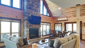 Un salon chaleureux avec une cheminée en pierre, des murs en bois et de grandes fenêtres.