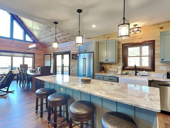 Una cocina amplia con una isla grande, armarios de madera e iluminación colgante.