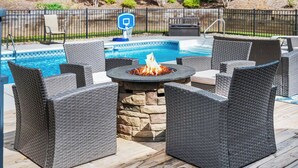An outdoor patio with wicker furniture, a stone fire pit, and a pool. - 8BR Resort Estate with Pool and Theater (Fletcher)