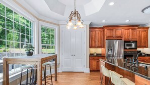 A spacious kitchen with wooden cabinets, a stainless steel refrigerator, and a large island with bar stools. - 8BR Resort Estate with Pool and Theater (Fletcher)