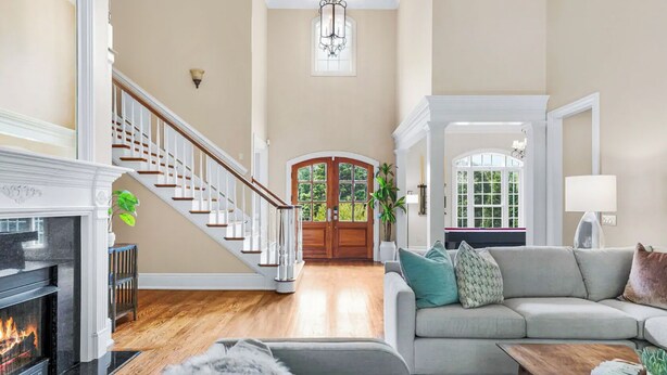 A spacious living room with a fireplace, a staircase, a large sofa, and a view of the outdoors. - 8BR Resort Estate with Pool and Theater (Fletcher)