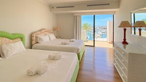 A hotel room with two beds, a dresser, and a balcony with a view of a marina.