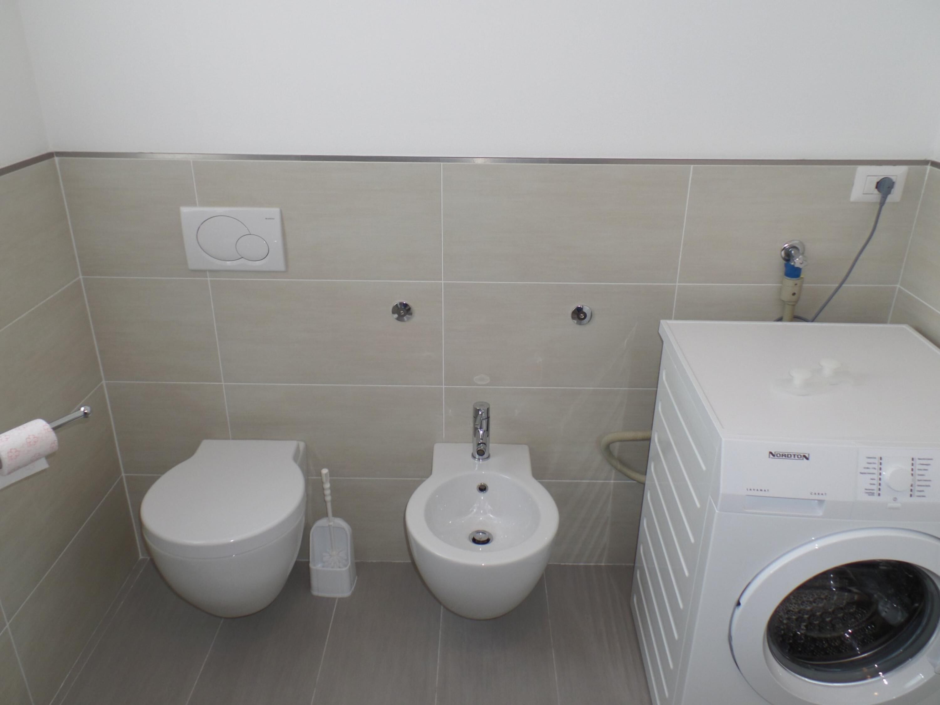 A bathroom with a toilet, bidet, and a washing machine.
