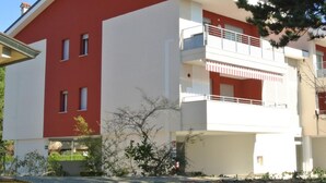 A two-story building with a red and white facade, balconies, and a green awning. - Lucia D in Bibione With 3 Bedrooms and 2 Bathrooms (San Michele al Tagliamento)
