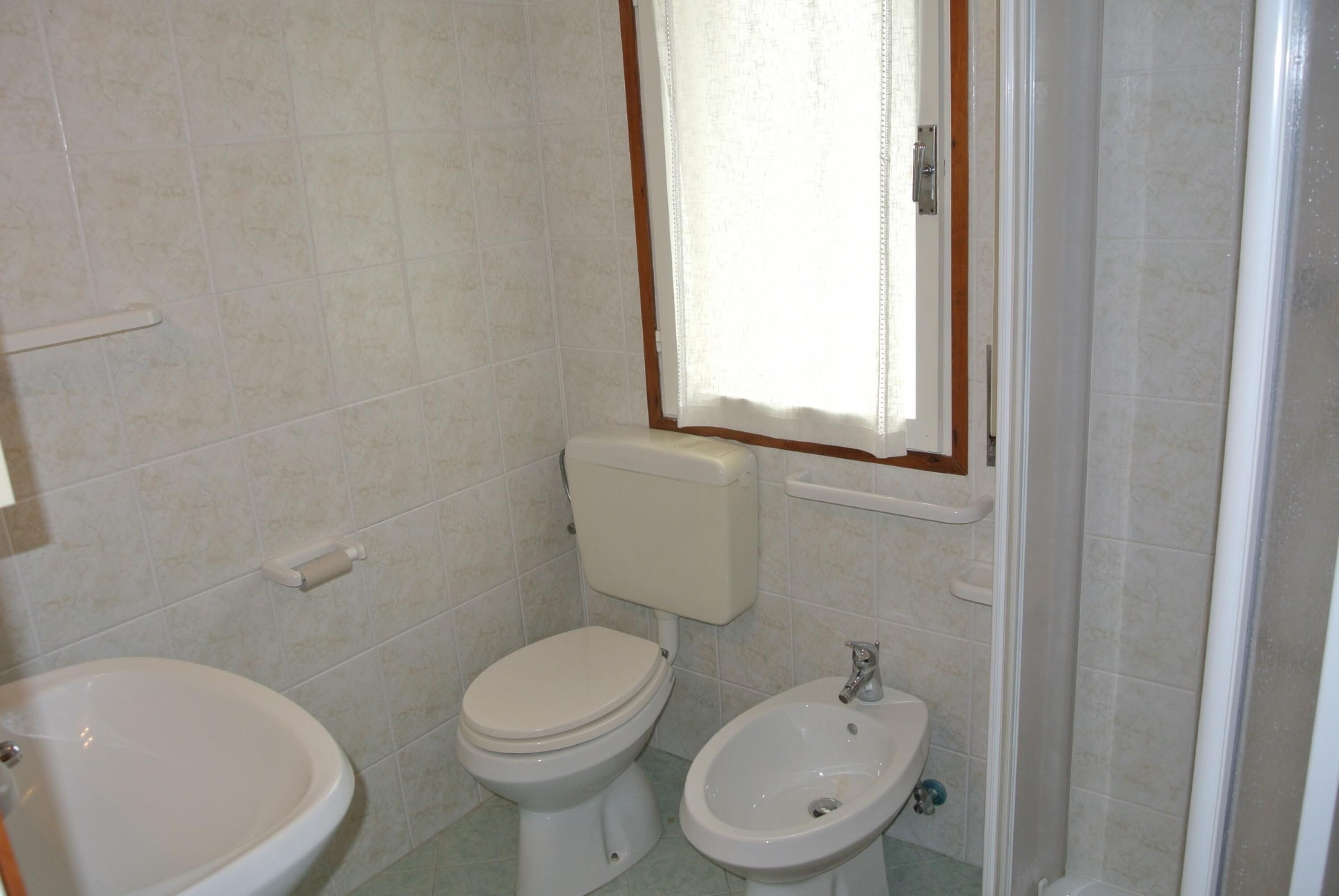 Une salle de bain équipée de toilettes, d’un bidet et d’un lavabo.