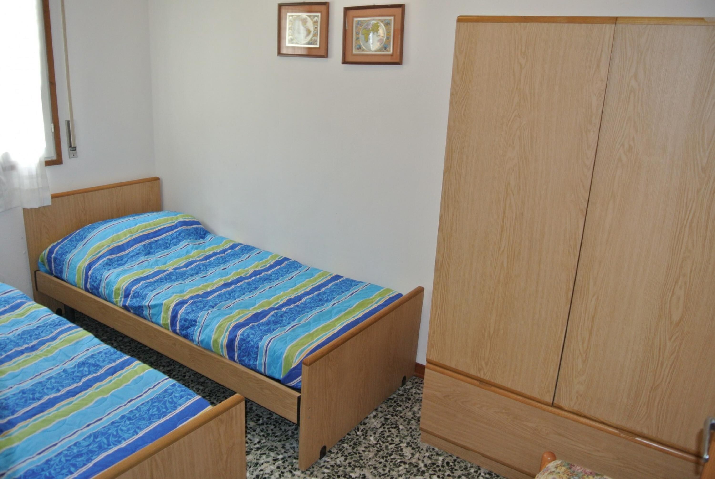 A bedroom with a bed, a wardrobe, and two framed pictures on the wall.