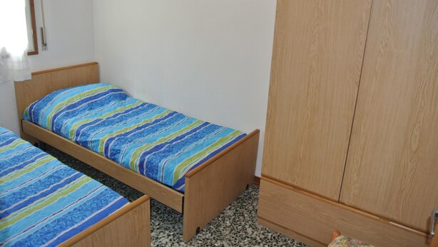 Un dormitorio con cama, un armario y dos cuadros en la pared.