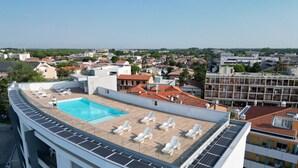 A rooftop pool with solar panels, lounge chairs, and a view of the cityscape. - Condominio Giardino C (San Michele al Tagliamento)