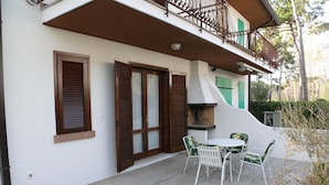 Un bâtiment doté d’un patio comprenant une table et des chaises, une cheminée et un balcon avec une balustrade.