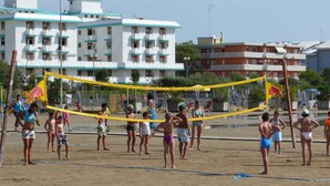Een strandvolleybalveld met spelers en toeschouwers.