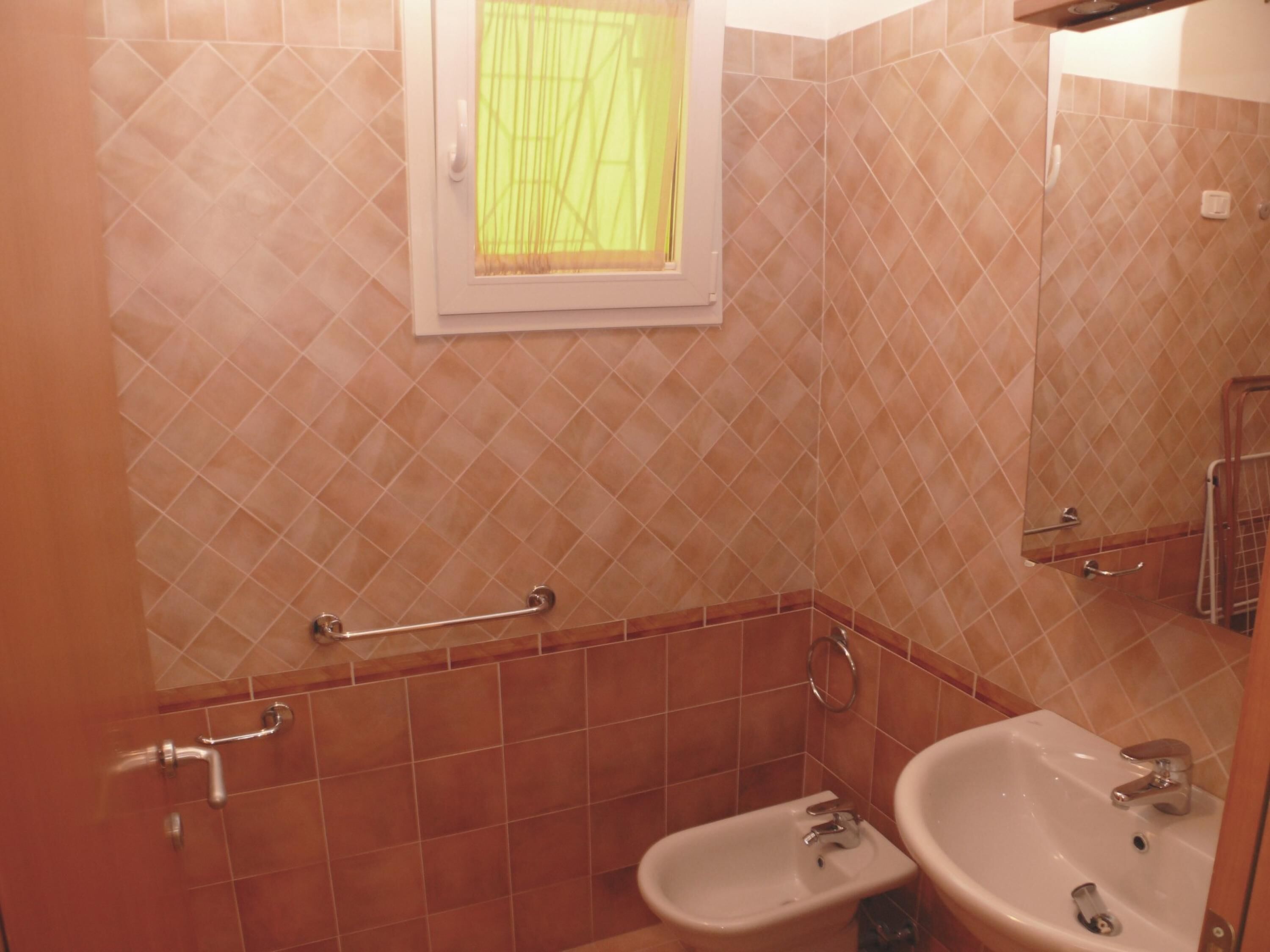 Een badkamer met een bidet, een wastafel en een spiegel.