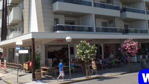 Un hôtel à plusieurs étages doté de balcons, d’un espace extérieur aménagé et d’une façade visible depuis la rue.