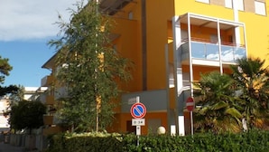 A yellow building with a balcony, a no parking sign, and a no entry sign. - Felice C in Bibione With 2 Bedrooms and 2 Bathrooms (San Michele al Tagliamento)