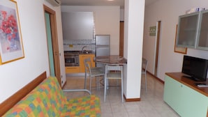 A compact living space with a kitchenette, a dining area, and a sofa. - Felice C in Bibione With 2 Bedrooms and 2 Bathrooms (San Michele al Tagliamento)