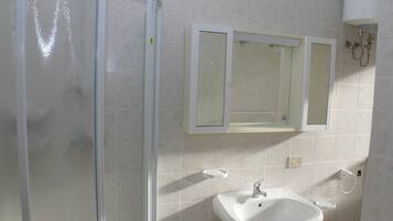 A bathroom with a shower, sink, and mirror.