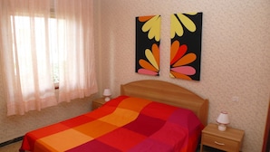 Ein Schlafzimmer mit einem Bett, zwei Nachttischen und einem Fenster mit Vorhängen.