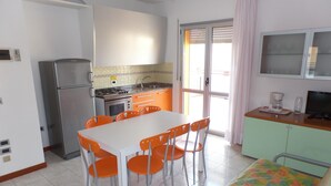 A compact kitchen with a dining table and chairs, a refrigerator, a stove, and a sink. - Felice C L in Bibione (San Michele al Tagliamento)