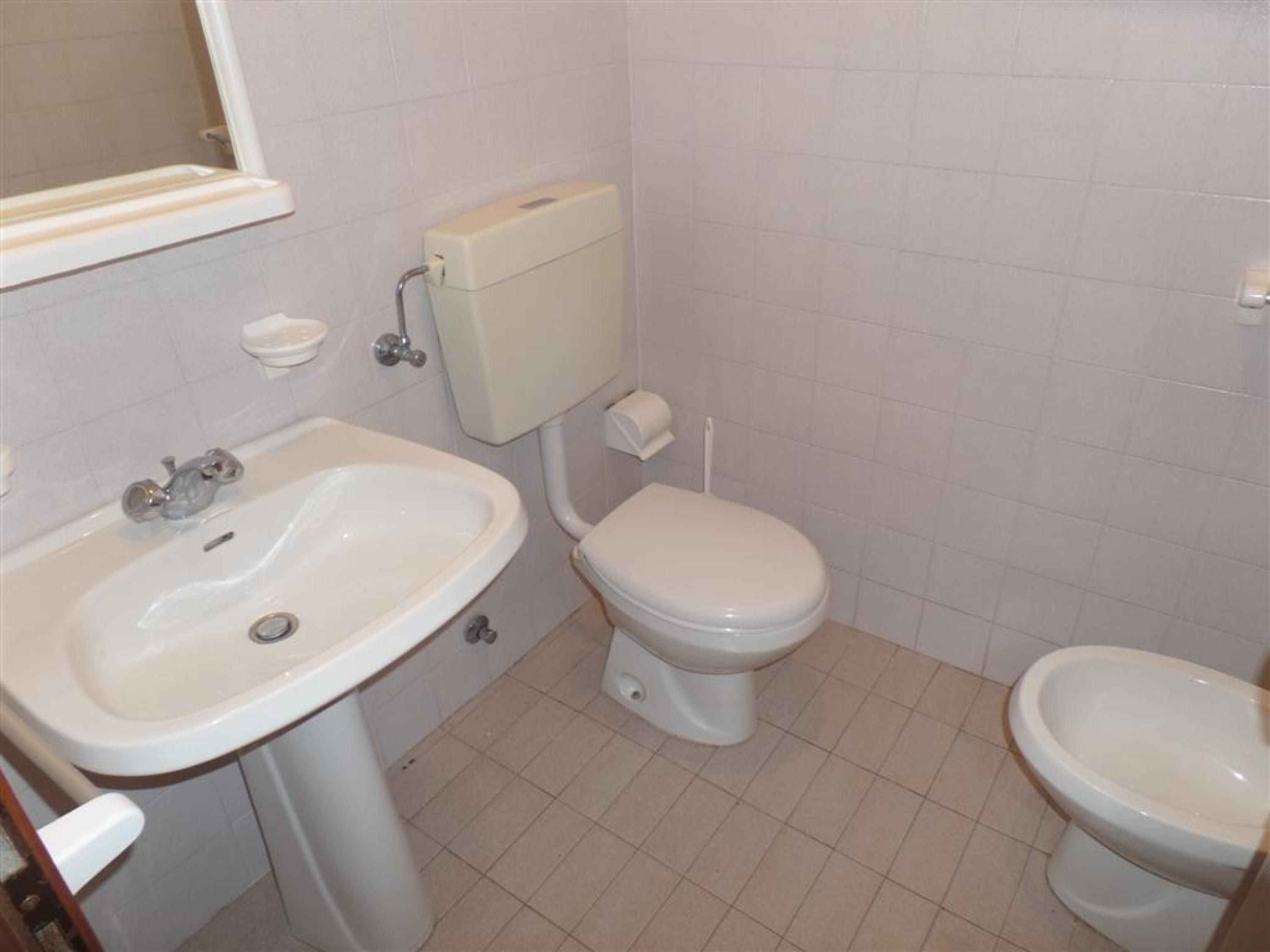 A small bathroom with a white sink, toilet, and bidet.