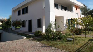 Une maison moderne à deux étages, dotée d’un toit plat, de grandes fenêtres et d’un chemin en briques menant à l’entrée.
