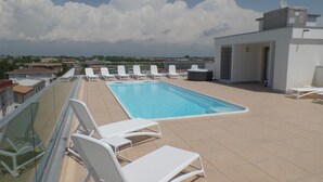 A rooftop pool with white lounge chairs and a clear view of the cityscape. - Quasar C in Bibione With 2 Bedrooms and 1 Bathrooms (San Michele al Tagliamento)