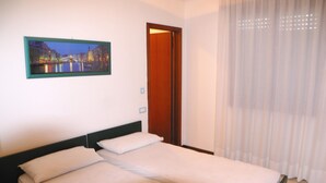 Ein Zimmer mit einem Bett, einer Tür und einem Bild an der Wand.