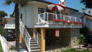 Een tweelaags huis met een balkon, een schotelantenne en een trap naar de bovenverdieping.