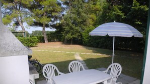 A patio with a white table and four chairs, an umbrella, and a barbecue grill. - Cometa 6 in Bibione With 2 Bedrooms and 1 Bathrooms (San Michele al Tagliamento)