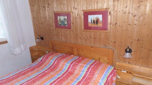 Ein Zimmer mit Holzvertäfelung, einem Bett, zwei Nachttischen und zwei gerahmten Bildern an der Wand.